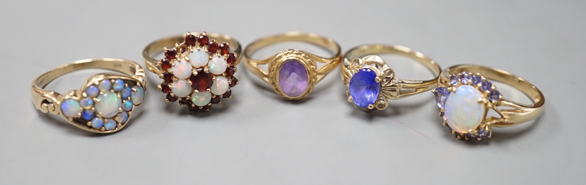 Five assorted modern 9ct gold and gem set dress rings, including, white opal cluster, garnet and white opal cluster and amethyst